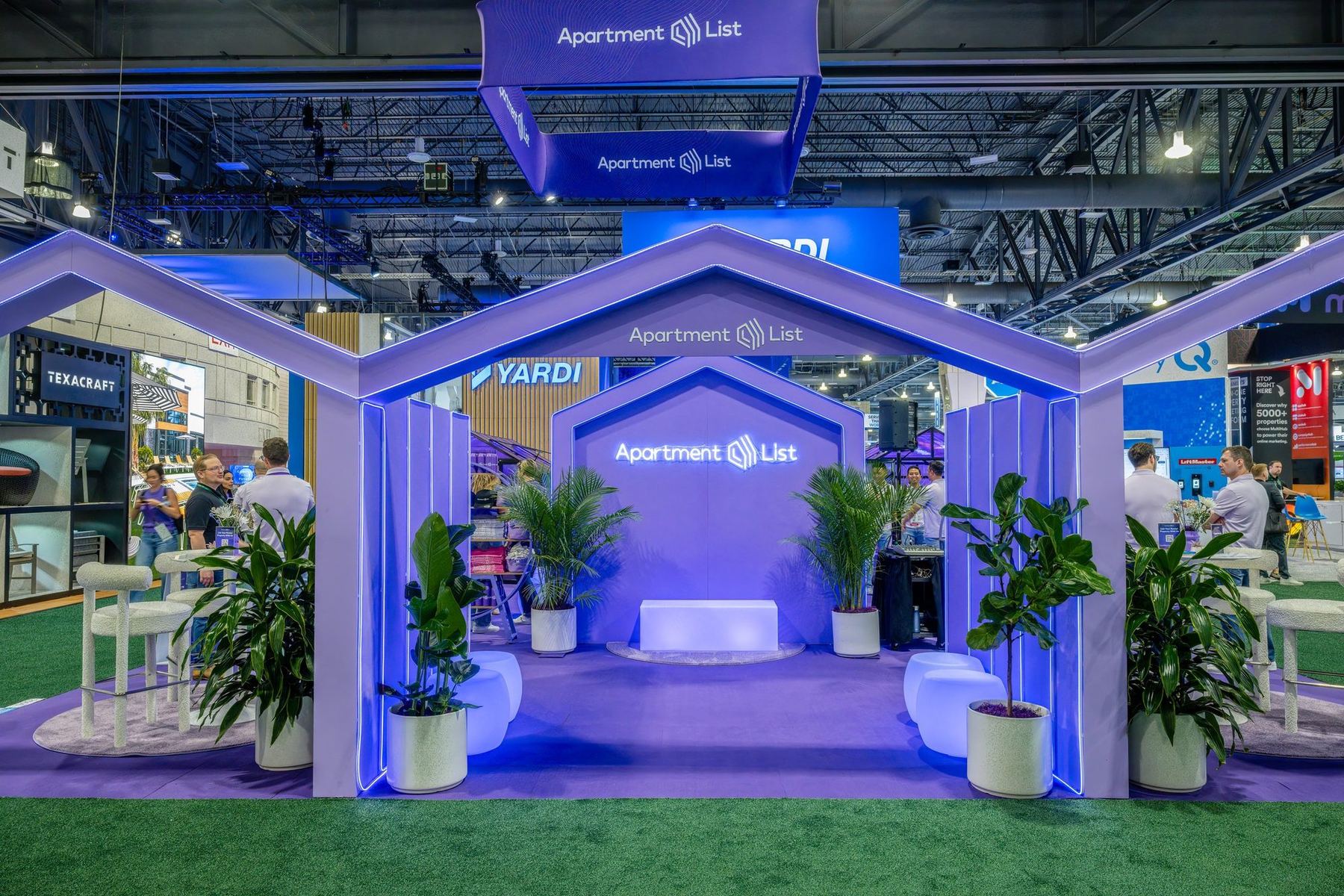 Apartment List trade show booth at NAA Apartmentalize 2024 with lit house-shaped arches and a greenhouse lounge