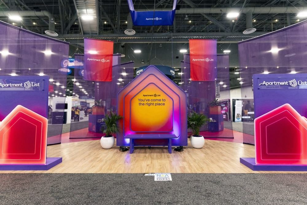 Apartment List booth at NAA Apartmentalize 2025 in Las Vegas with gradient house-shaped panels and a central doorway