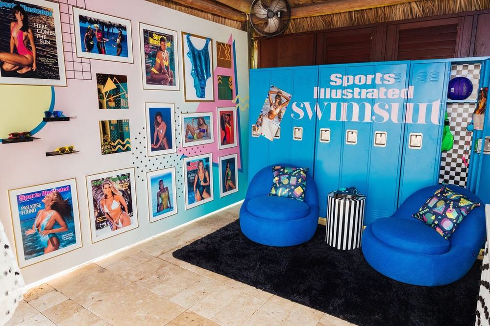 SI Swimsuit cabana with blue lockers, a wall of archival swimsuit covers, and blue lounge chairs