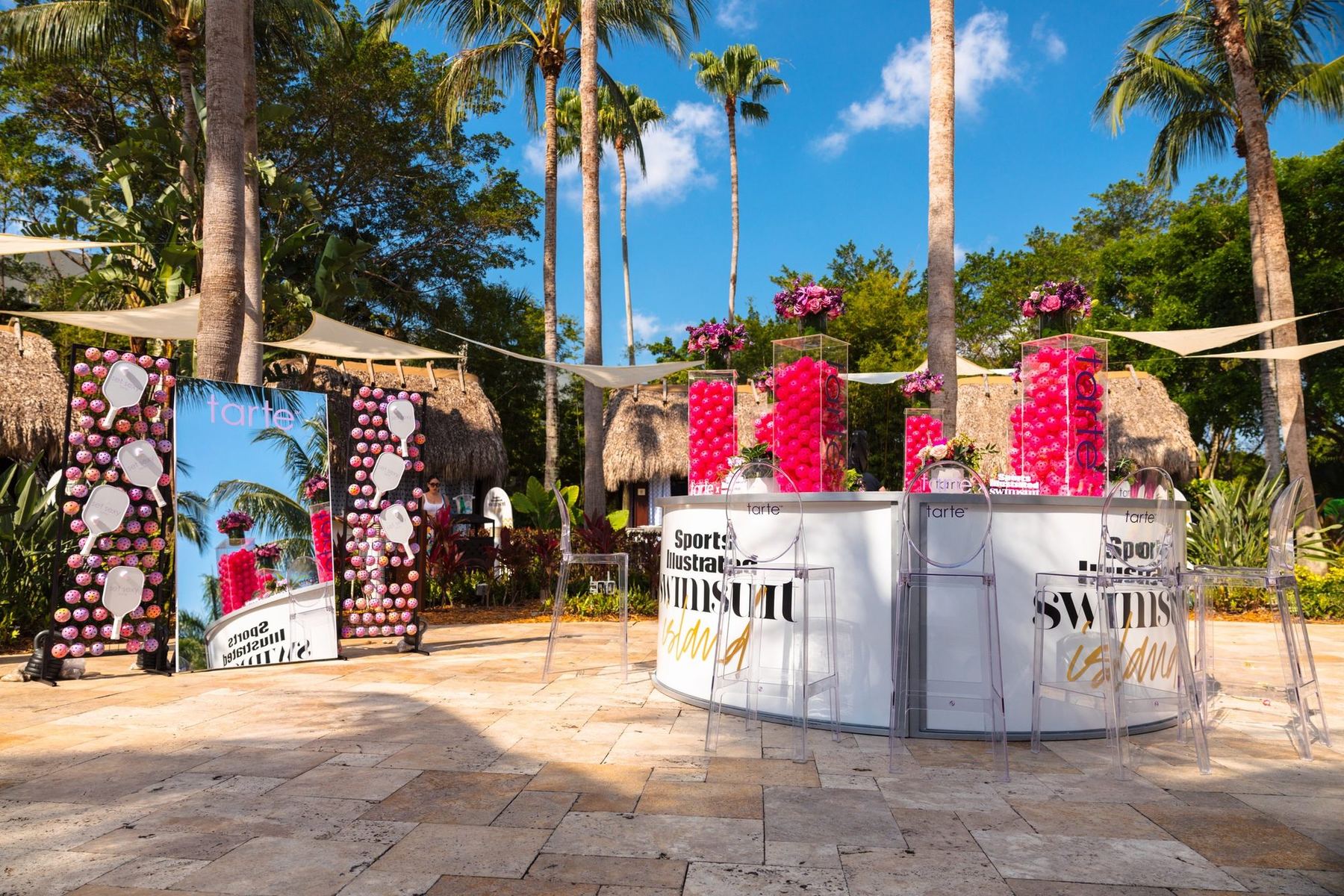 Outdoor bar at SI Swimsuit Island with palm trees, pink florals, and Sports Illustrated Swimsuit branding at Seminole Hard Rock Hollywood