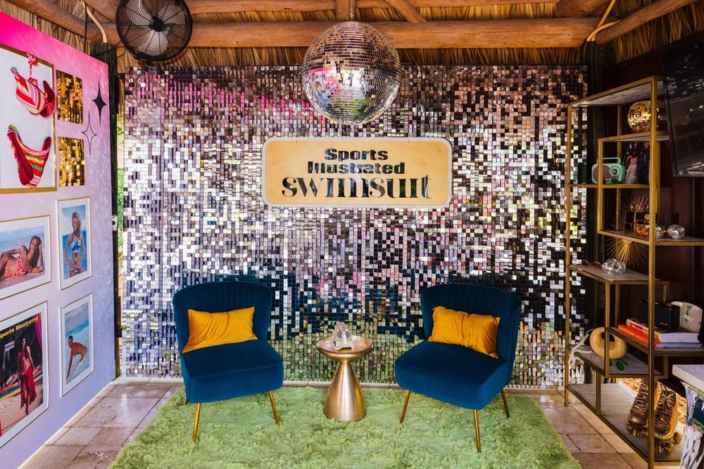 1970s-themed SI Swimsuit cabana with a sequin wall, disco ball, and blue velvet chairs